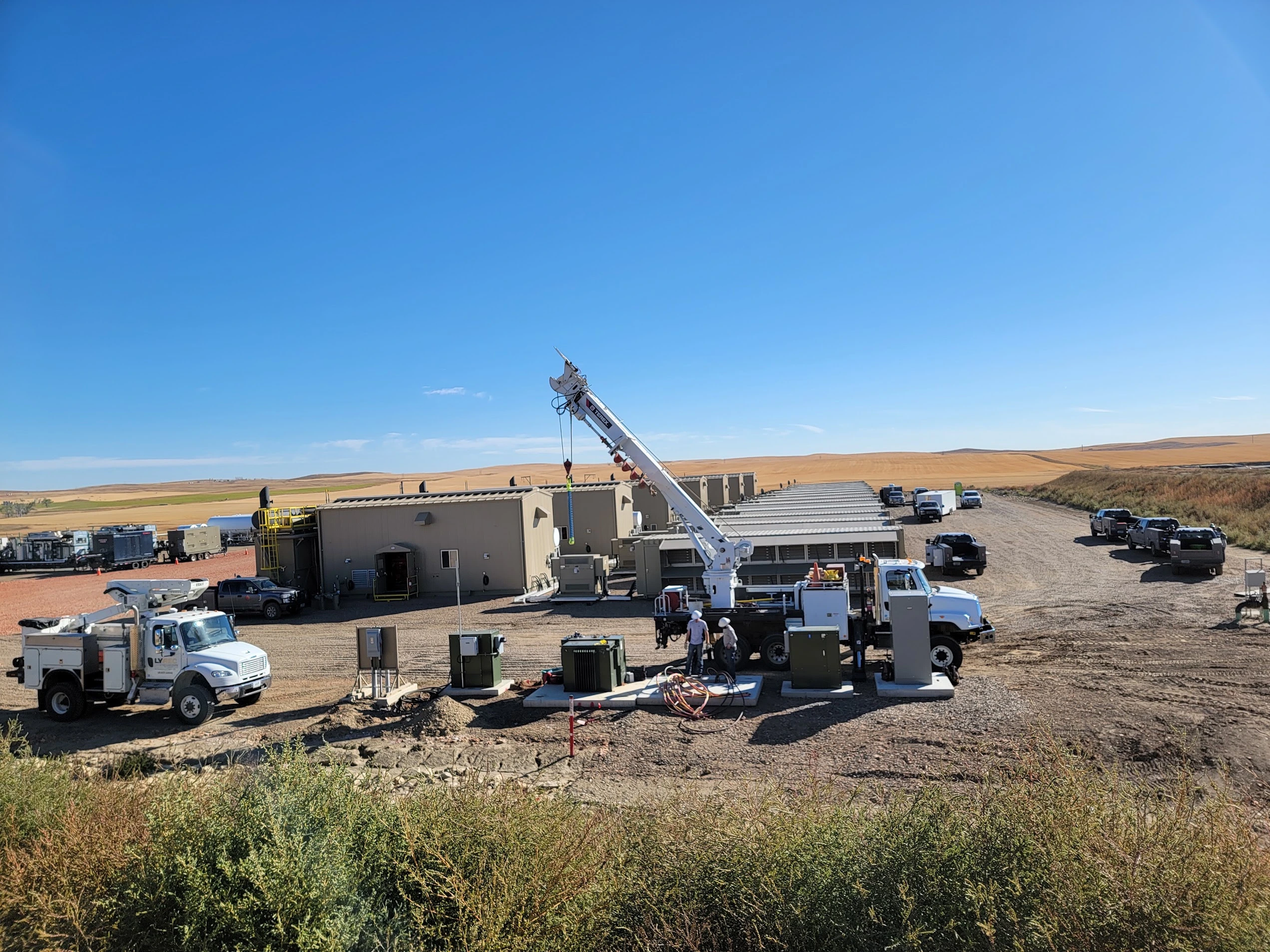Crusoe modular data centers (MDUs) with service trucks and a crane